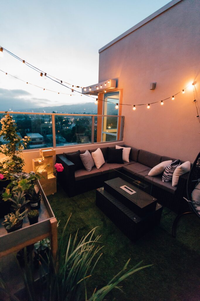 Aménager un balcon : des plantes, un canapé, de la pelouse synthétique, une guirlande lumineuse